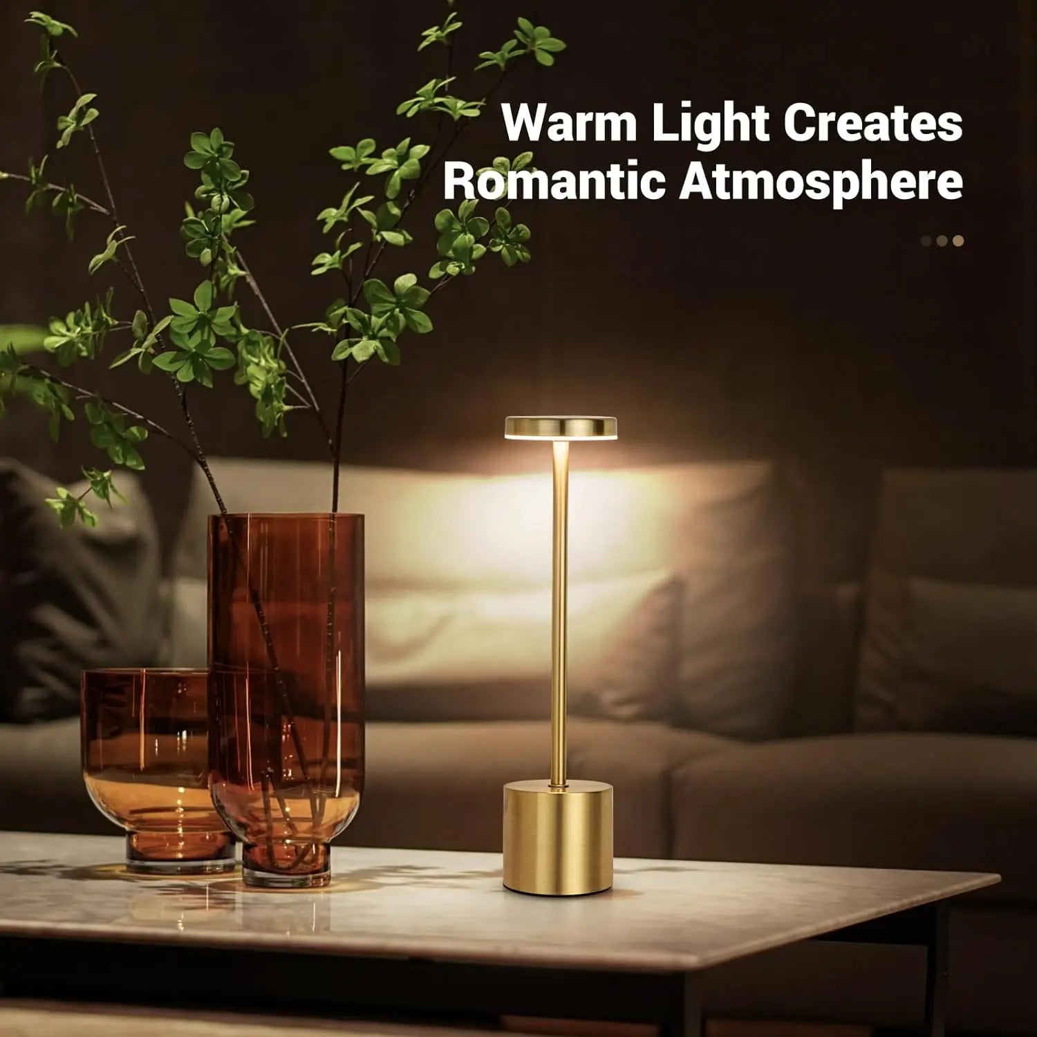 Gold table lamp on a marble surface with decorative glasses and a vase, text 'Warm Light Creates Romantic Atmosphere' above.
